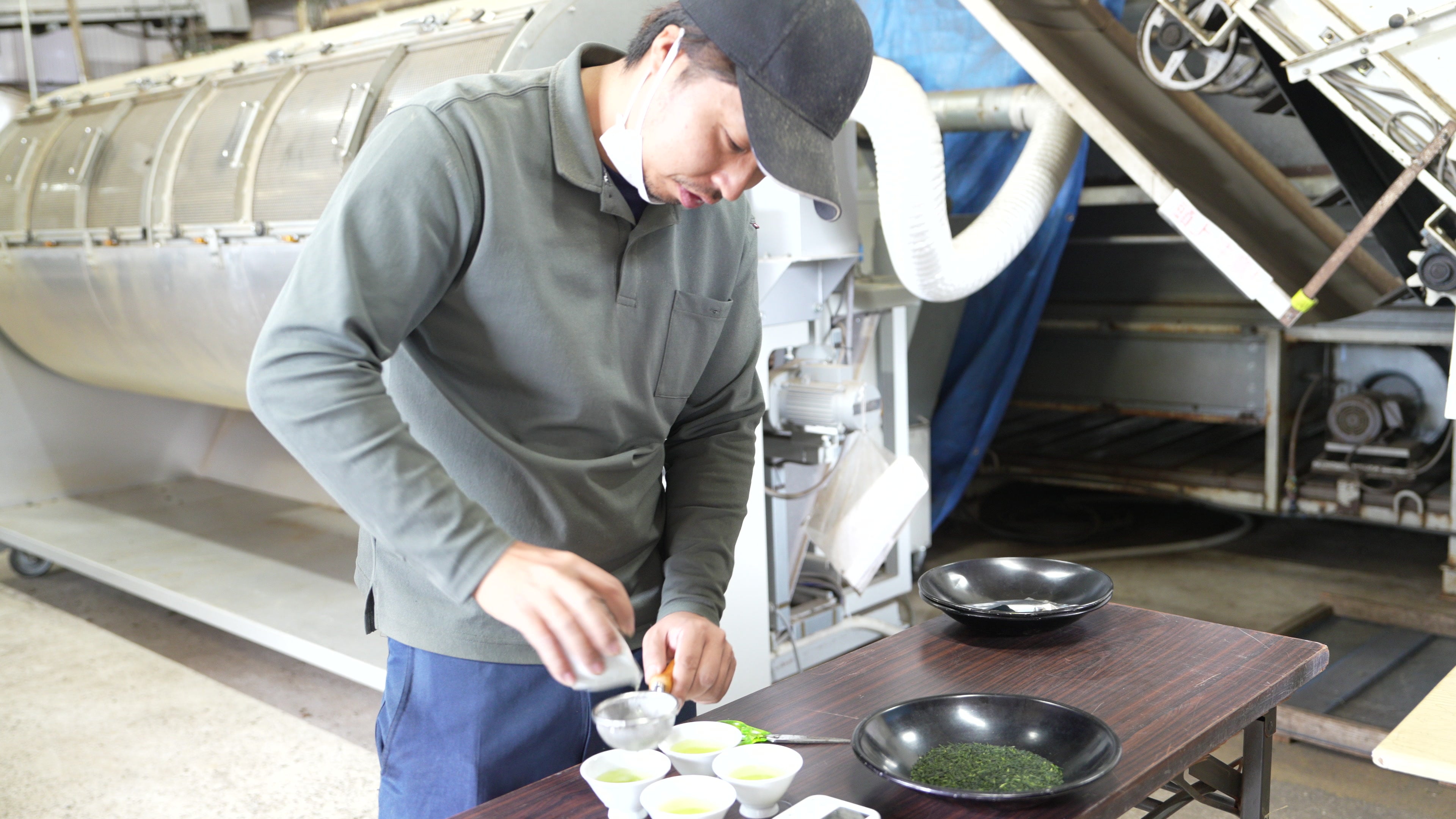 A Japanese tea producer evaluating leaf and liquor colour at a cupping bench