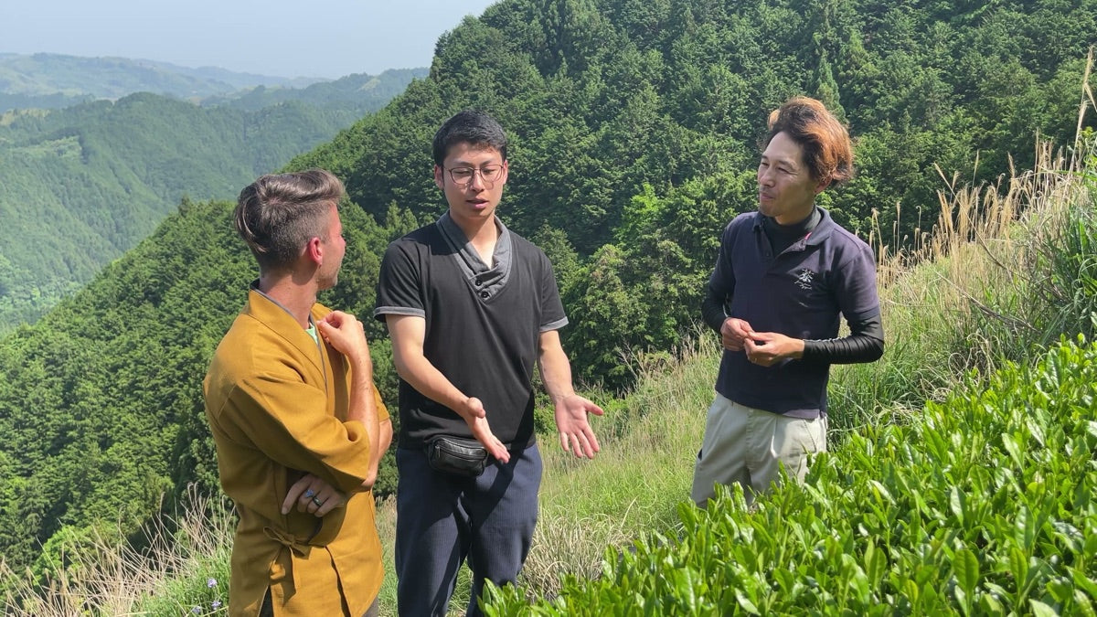 Christian Mauerer with Jiro-san on a Shizuoka mountain ridge above the Houkouen tea fields, three figures in conversation