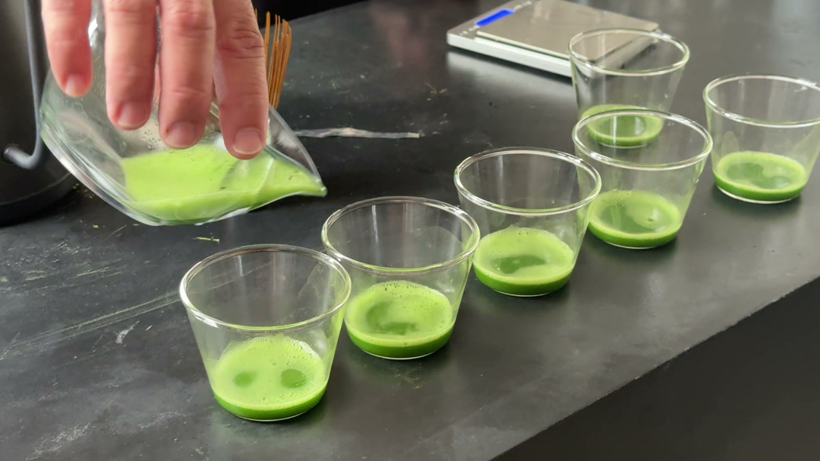 Bright green matcha poured into a row of tasting glasses
