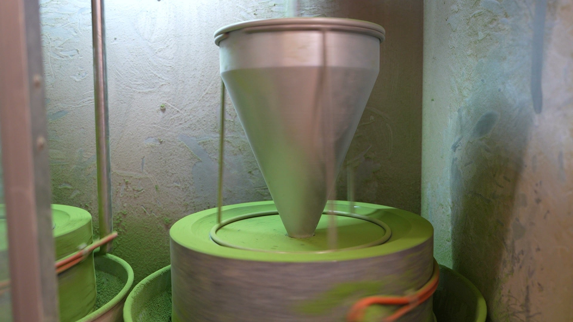 Granite stone mill slowly grinding tencha into bright green matcha powder, the traditional method behind matcha's history