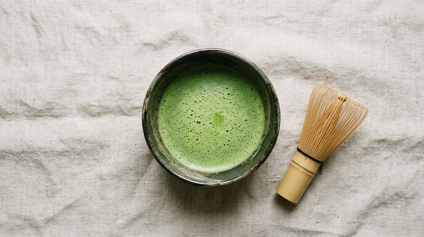 A bowl of freshly whisked bright green ceremonial matcha with a bamboo whisk on neutral linen, evoking calm and stress relief.