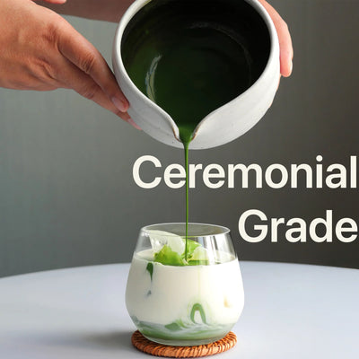 Organic ceremonial matcha powder being poured into a glass, showcasing its vibrant green color and creamy texture.